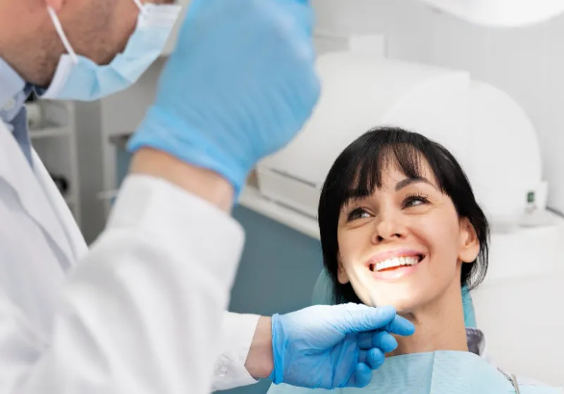 Odontóloga atendiendo a una paciente sonriente en un box dental