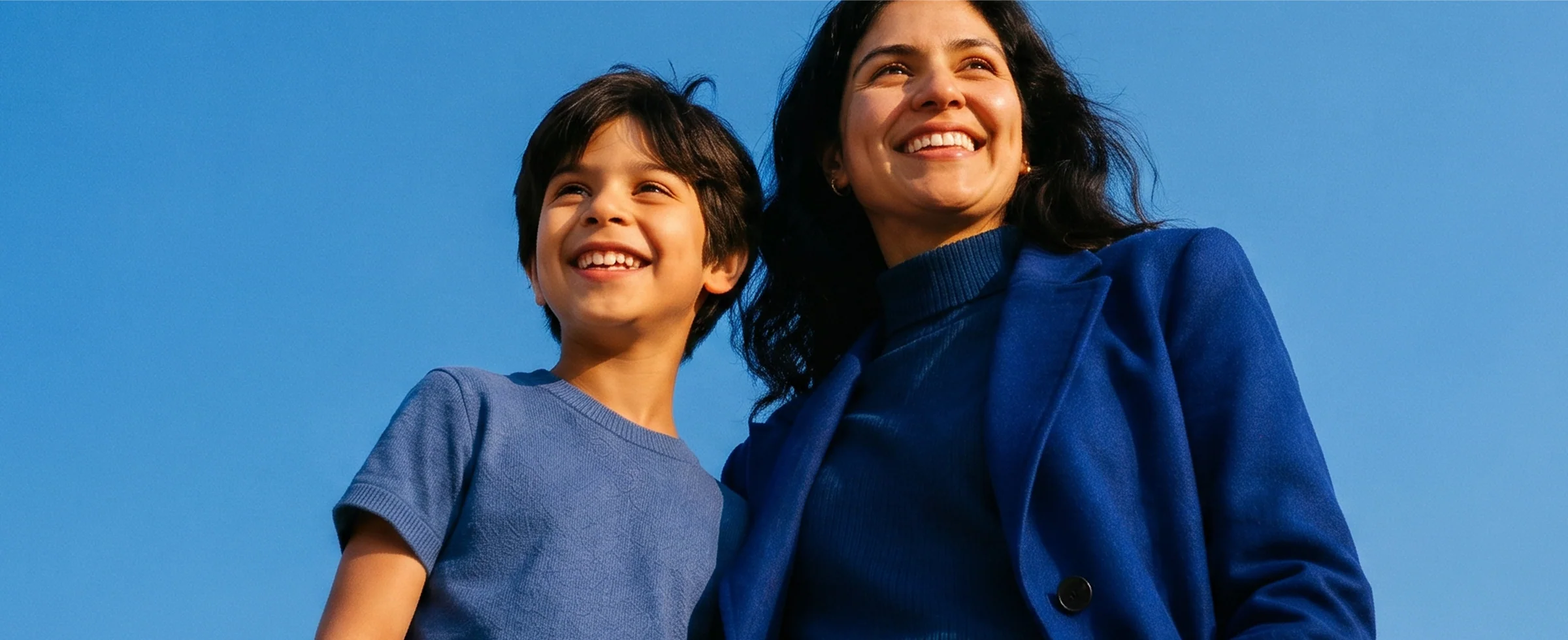 Mamá e hijo sonriendo bajo un cielo azul — Promociones dentales IntegraMédica.